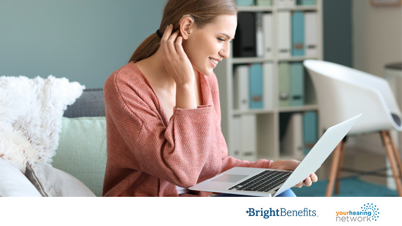 Young woman with hearing aid looking a laptop